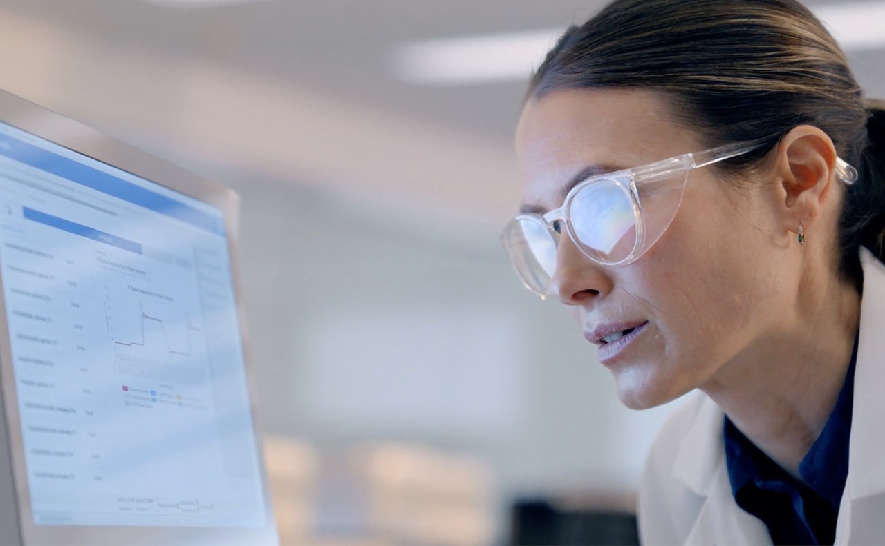 Close up clip of female scientist closely looking at the screen of a NextSeq 1000/2000 sequencer, additional hand of a different scientist not visible explaining results.